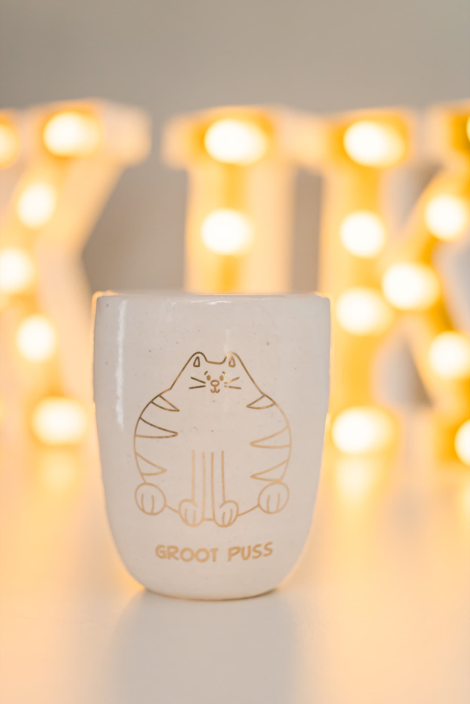 The Groot Puss cup in front of the lit-up KJK letters